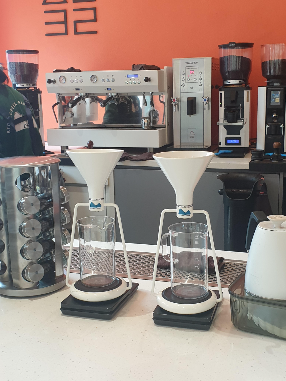 뒤에 에스프레소 머신과 그라인더 앞에는 드리퍼와 서버 그리고 드립포트가 보인다.