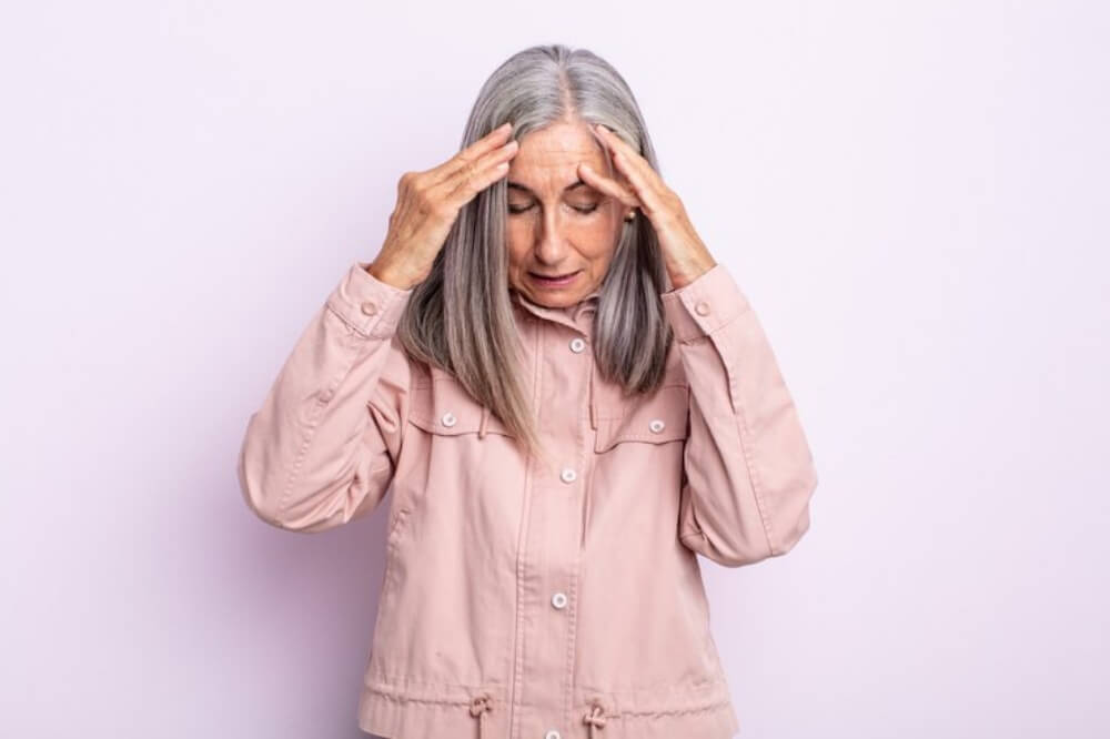 할머니가 두통때문에 두손을 이마에 대는 모습