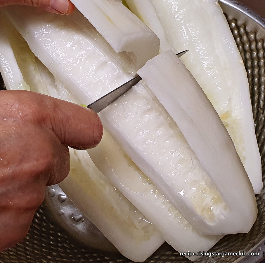 노각 무침을 하기 위해 씨앗을 제거한 긴 노각살을 반으로 자르는 사진