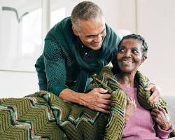 노인에게 담요를 덮어주며 따뜻하게 웃고 있는 모습