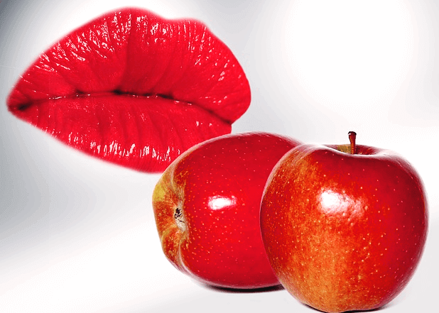 빨간 립스틱을 바른 촉촉한 여자 입술과 탐스러운 빨간 사과 2개가 나란히 있다.