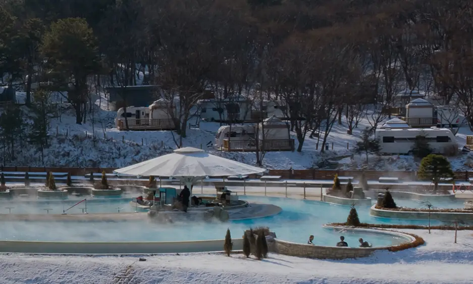 겨울방학 국내 여행지-
겨울 흰눈이 쌓인 초록 숲 앞 연기가 나는 수영장