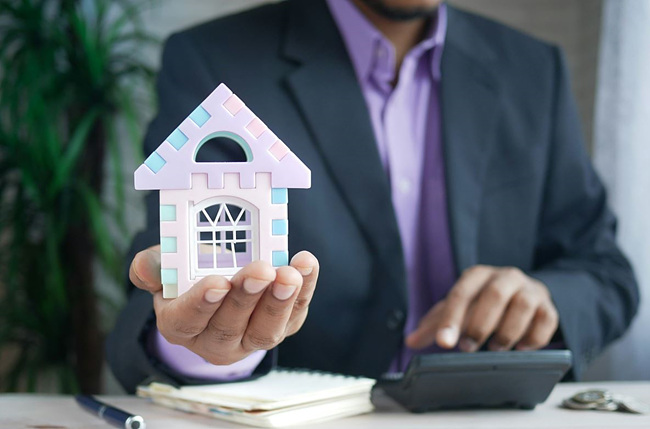 집 모형을 들고 있는 양복 입은 남자 사진