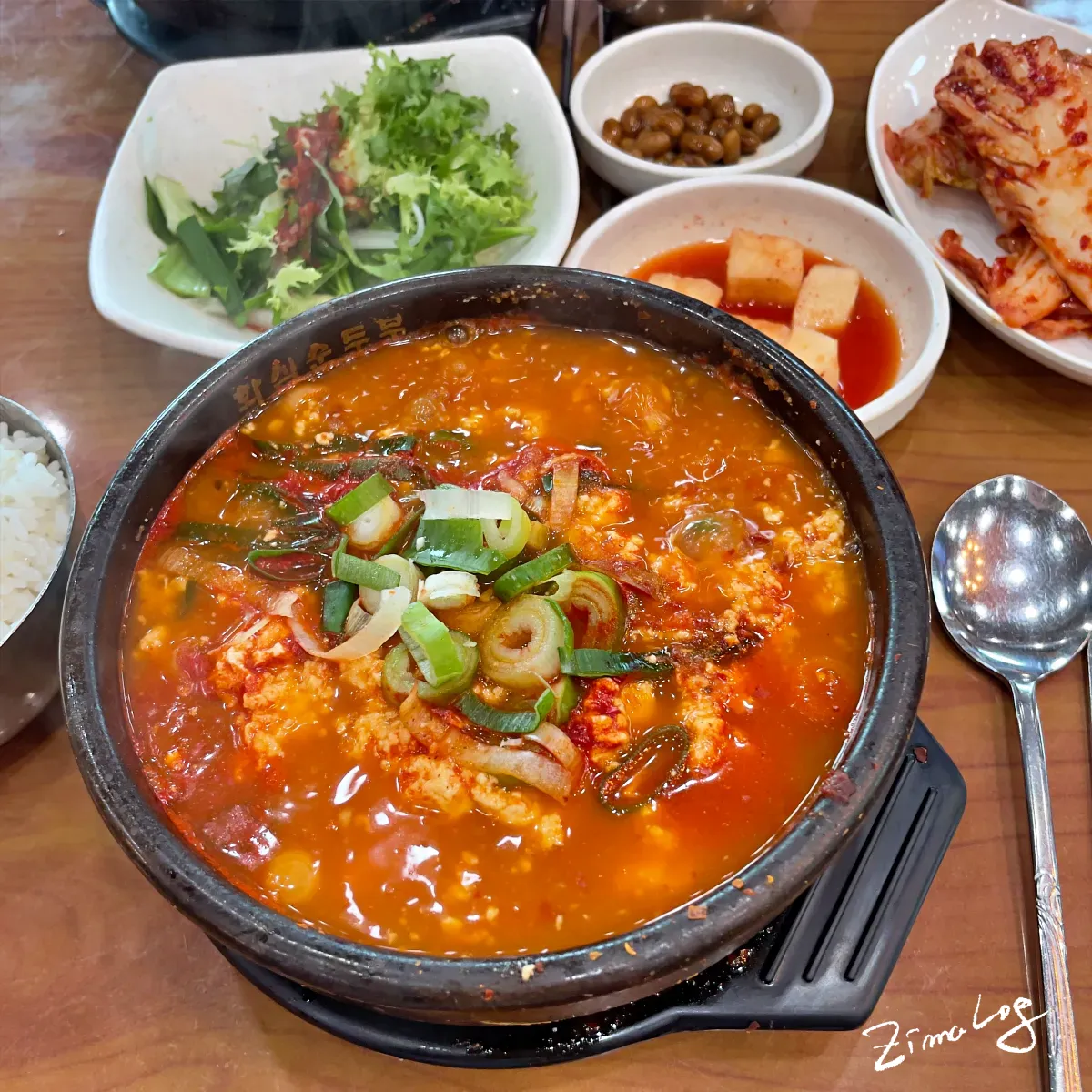 바지락 순두부찌개의 모습으로 찌개에 순두부와 국물이 가득들어 있고 대파가 올라가 있음