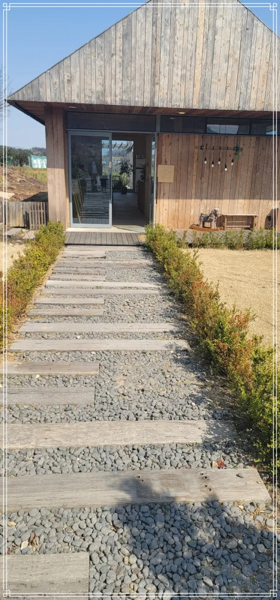 예산-백설농부-건물-입구가-보이고-진입로가-자갈과-징검다리-모양으로-깔려-있다