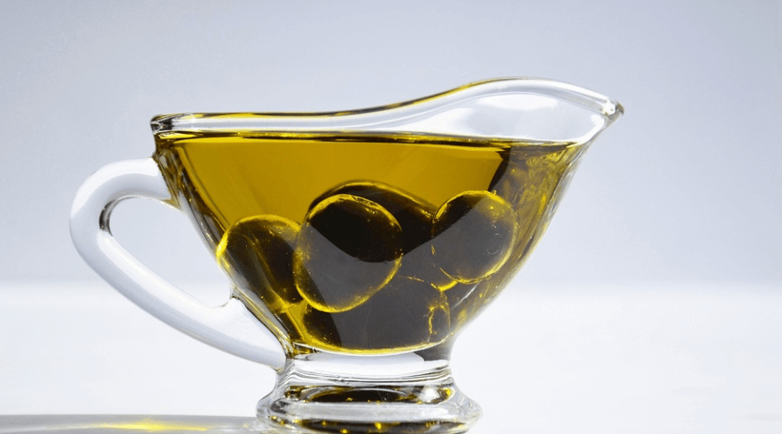 컵에 올리브와 올리브 오일이 담겨 있다