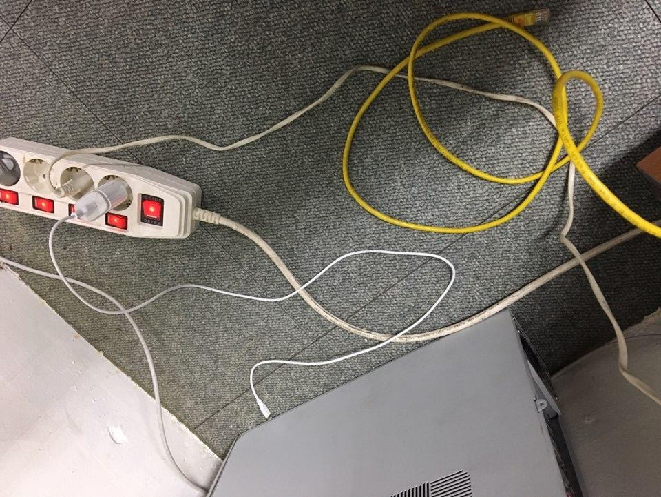 바닥에 엉킨 노란색, 흰색 케이블과 멀티탭이 있는 지저분한 사무실 바닥