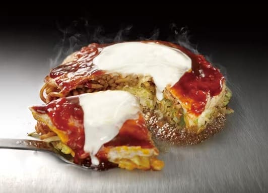 철판위에 음식이 올려져 있고 그 음식의 단면이 잘려져 김이 나오고 있다.