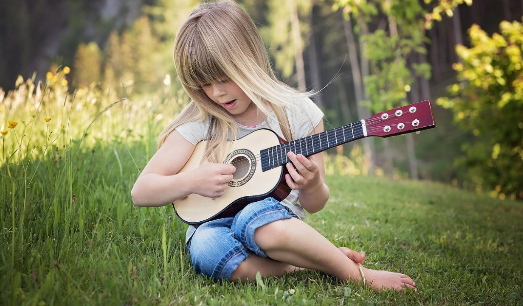 음악기반 감성교육의 실제 예시_잔디 위에서 악기 연주하는 아이