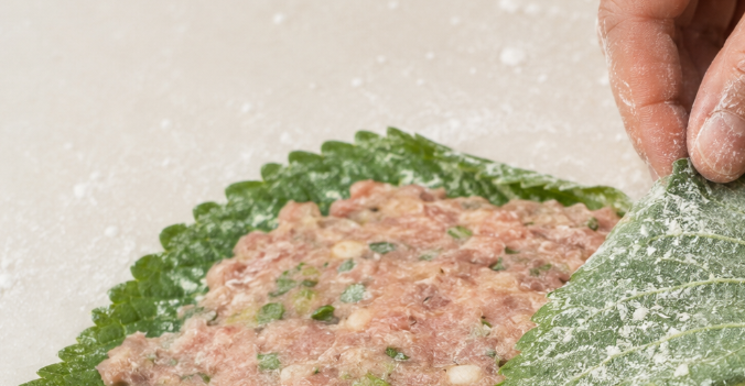 전분이 묻은 깻잎 반면에 분홍빛 고기 소가 도톰하고 평평하게 올려지고, 반대편 깻잎이 사뿐히 접혀 반달 모형으로 정갈하게 완성