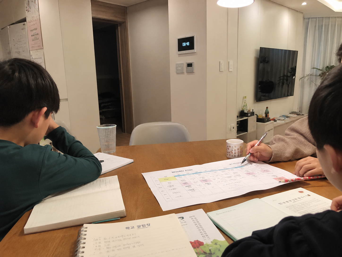 식탁에서 초등학생 학원 일정표를 확인하는 엄마의 손