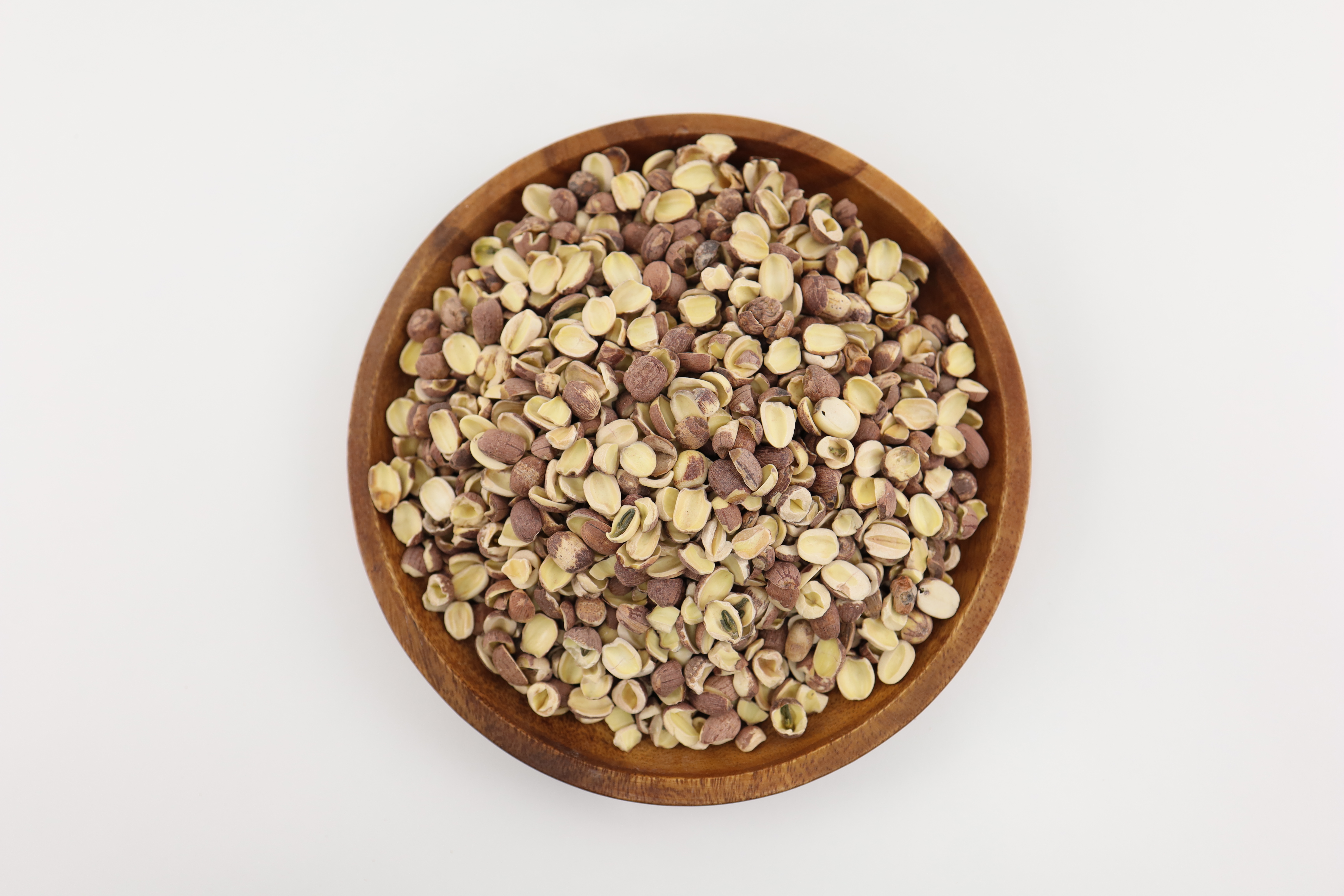 야생에서 채취를 한 연꽃 열매를 깨끗하게 세척하여 발려서 반으로 쪼갠 연자육을 고동색의 동그란 나무 그릇에 가득 담아서 하얀 바닥에 놓아두고 찍은 사진