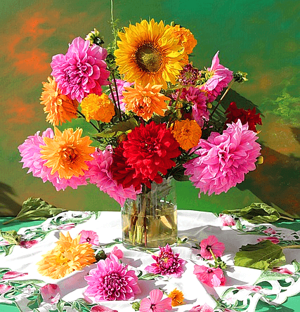 투명한 유리병에 노란 해바라기꽃, 분홍 국화, 노란 국화, 붉은 카네이숀이 가득 들어있다.