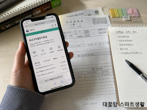 청년구직활동지원금 신청 페이지를 스마트폰으로 확인하는 모습