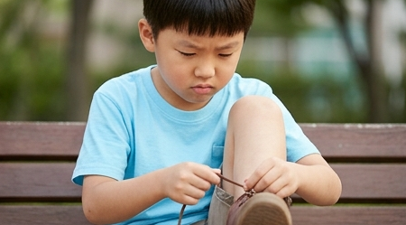아이가 혼자 신발끈을 묶으려 애쓰는 모습