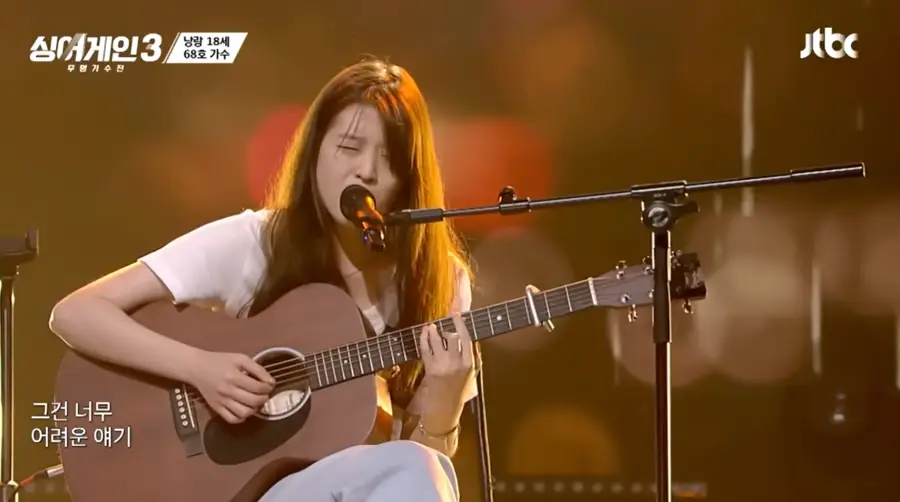 싱어게인3-
흰색 반팔티를 입고 갈색기타를 치며 머리를 풀어헤치고 회색바지를 입은채 의자에 앉아 스탠딩마이크에 입을 대고 눈을감고 노래하는 68호