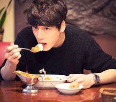 검은-티를입은-멋진-남자가-포크로-요리를-찍어-입에-넣고있는-멋진-모습