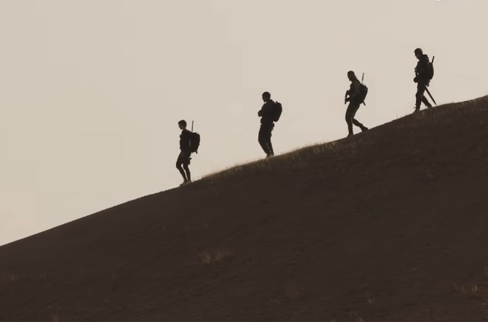 Four Old Guards were walking down the ridge in the desert.