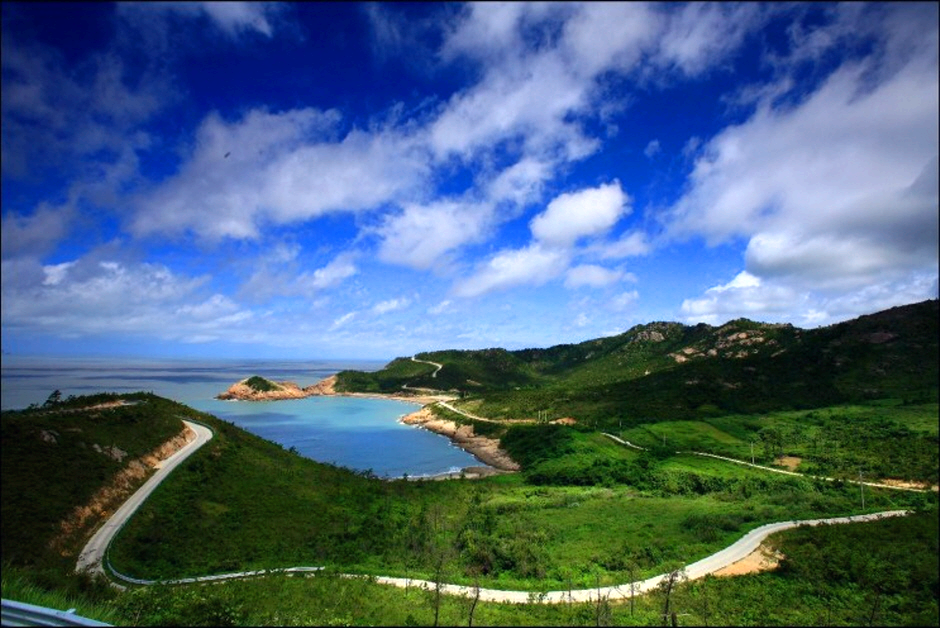 파란하늘 아래 하트모양 해수욕장과 푸른 들판이 있다.