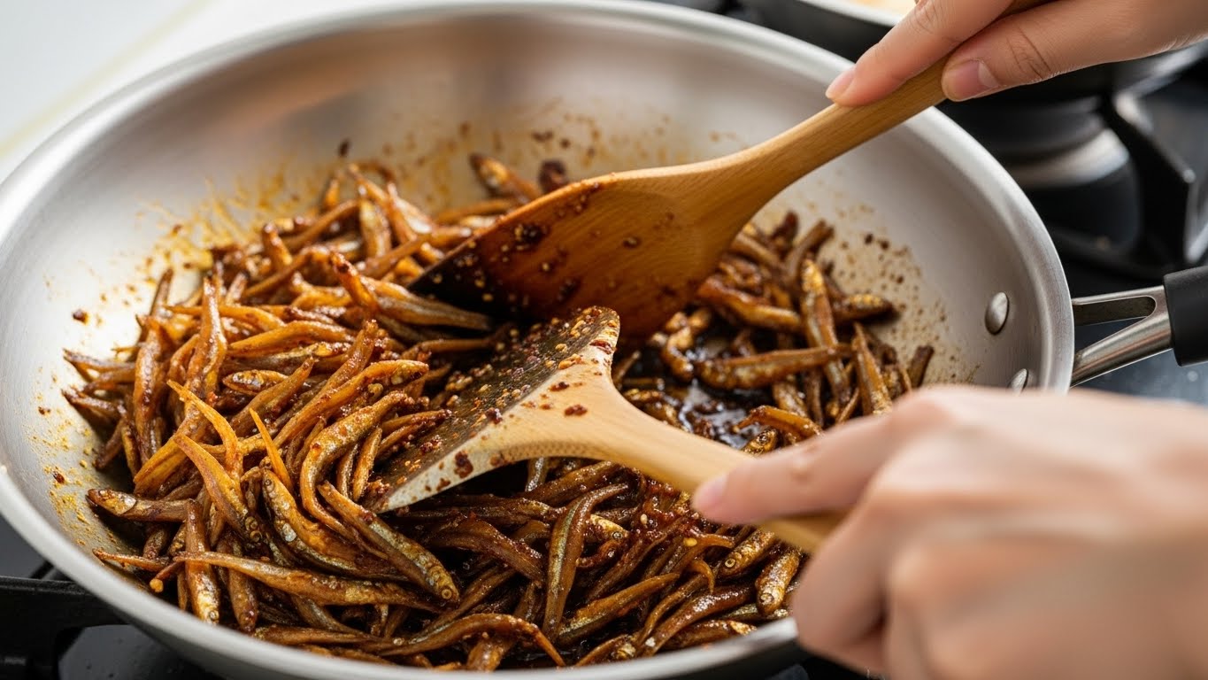 볶은 멸치에 양념을 넣고 빠르게 섞는 과정
