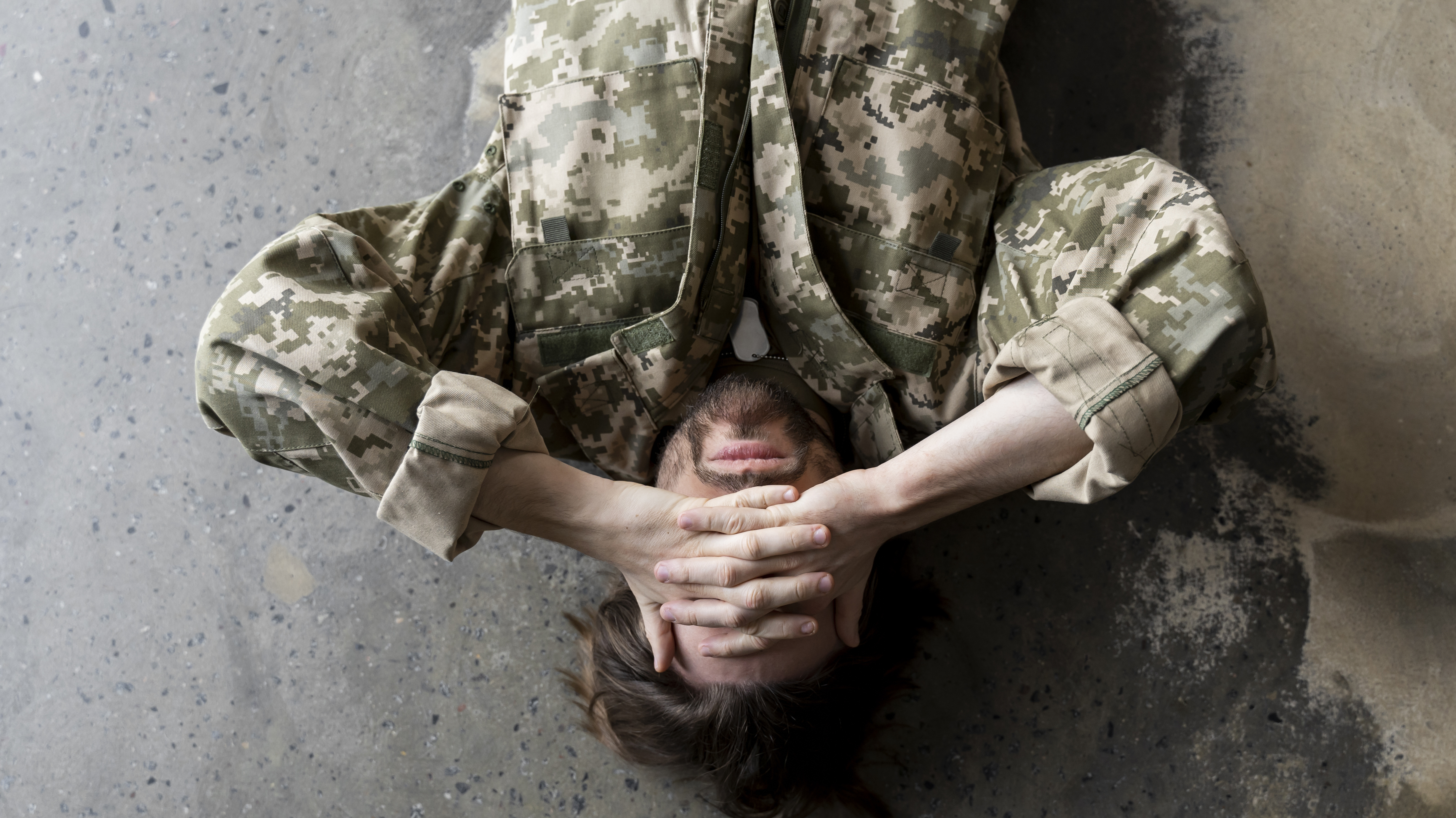 깍지 낀 두 손으로 눈을 가리고 누워있는 군인
