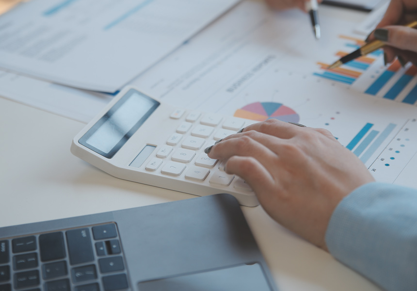 계산기와 서류를 통해 주식 거래 수수료를 계산하는 모습