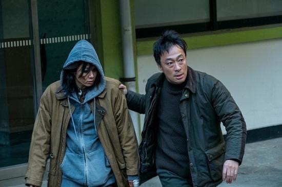 영화 《비스트》에서 진실을 파헤치려는 형사가 피투성이가 된 인물을 이끌고 사건의 중심으로 향하는 장면. 폭력과 의심, 그리고 선택의 딜레마가 교차하는 순간이다.