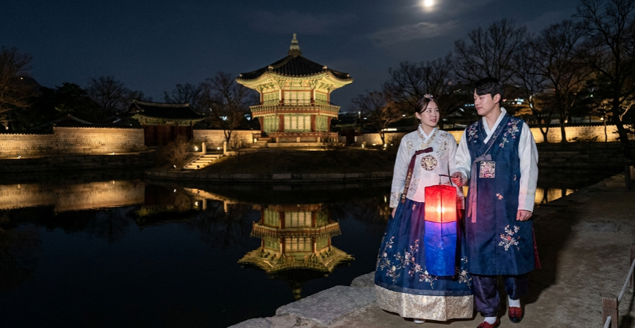 한복을 입은 커플이 경회루 앞에서 청사초롱을 들고 웃고 있는 모습