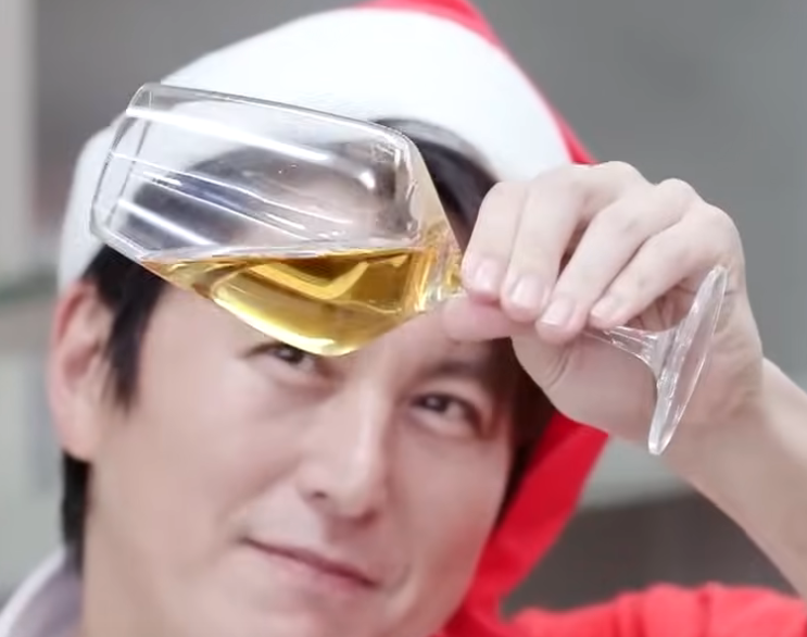 산타모자를 쓴 사람이 와인잔을 들고 있다.