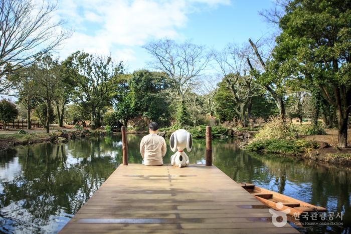호숫가 나루터에 스누피캐릭터와 남자가 앉아있다.