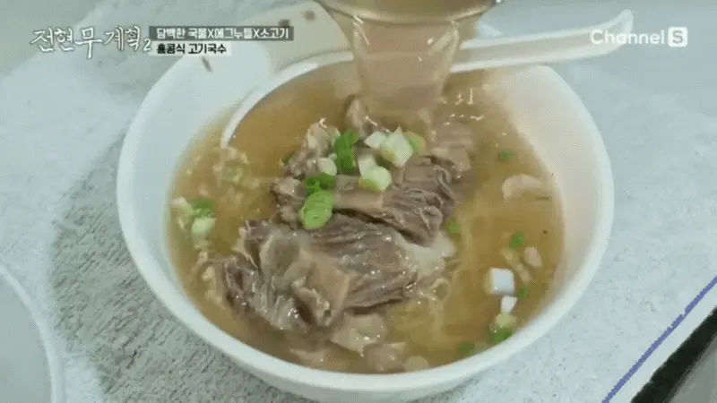 면 위에 큼지막한 고기가 듬뿍 올려져 있는 고기국수 그릇에 양지 육수를 가득 붓고 있는 모습