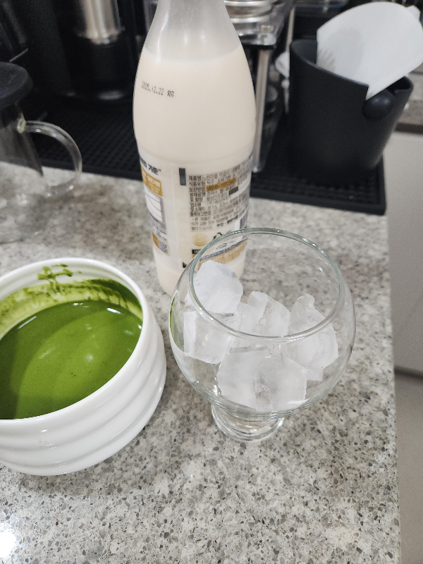 물에 푼 말차와 얼음이 담긴 컵 그리고 막걸리가 놓여 있다.