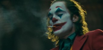 조커 영화 속 광대 분장을 한 아서 플렉이 담배를 피우는 어두운 장면