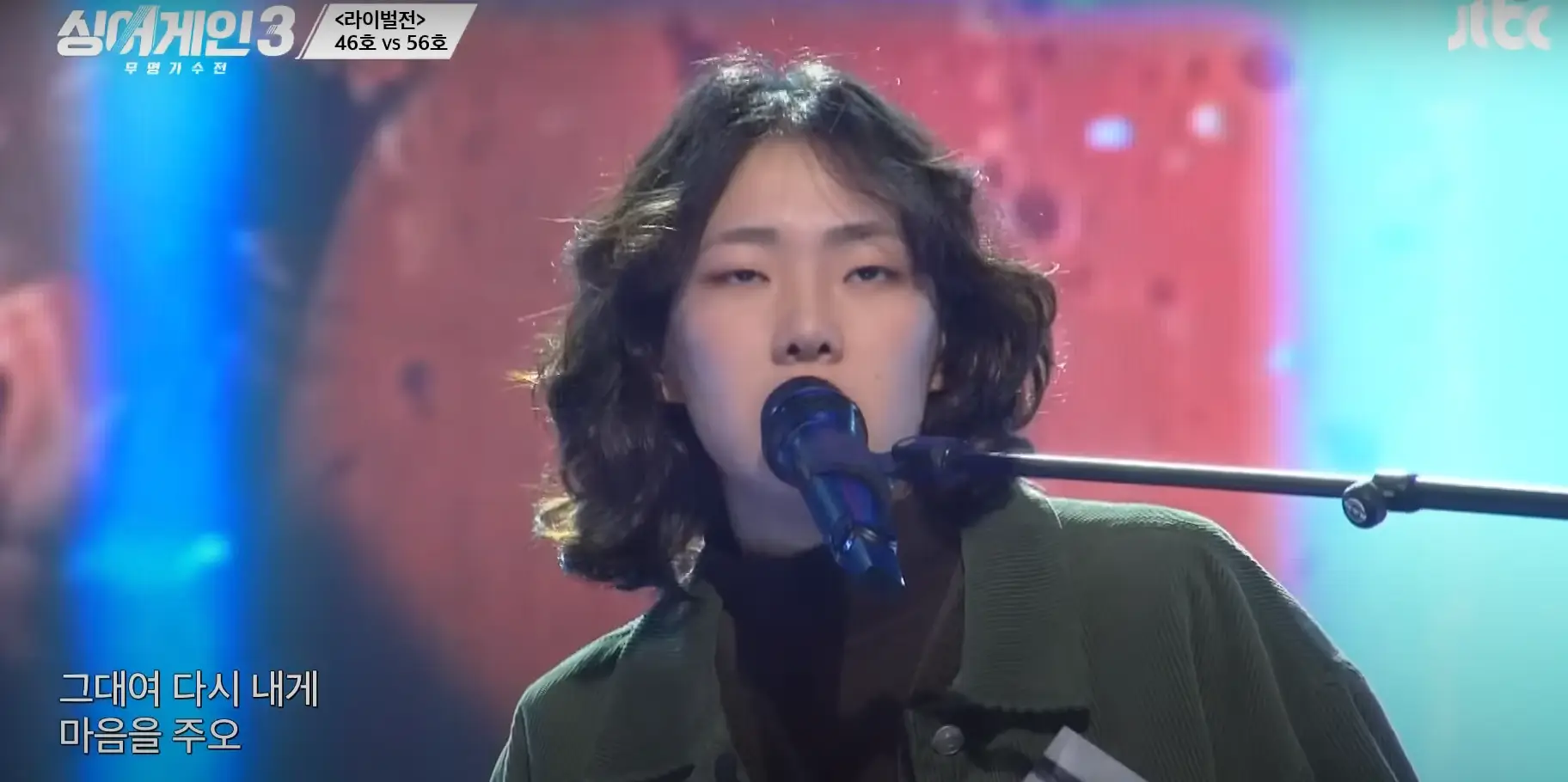 싱어게인 3- 초록색 자켓을 입고 곱슬단발머리로 스탠딩마이크앞에서 노래하는 56호 상반신