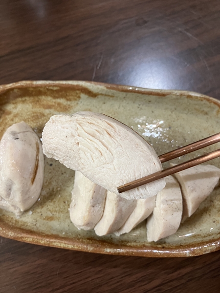 젓가락으로 수지스 그릴드 닭가슴살을 집은 모습 &ndash; 단면 식감이 드러난 장면