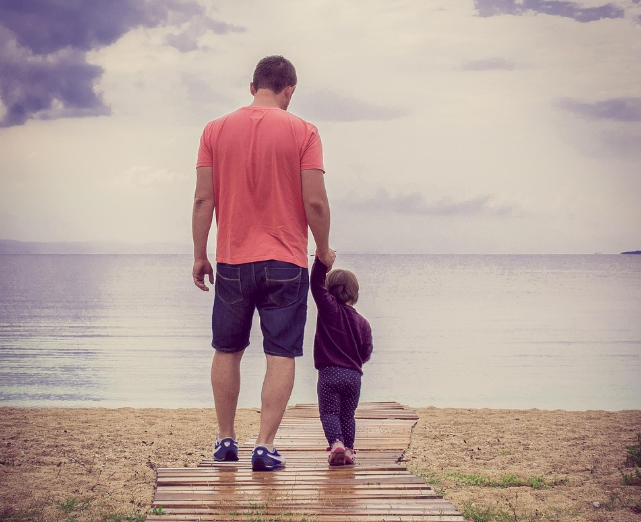 해변 산책로에서 아버지와 아이가 손을 잡고 함께 걷는 모습