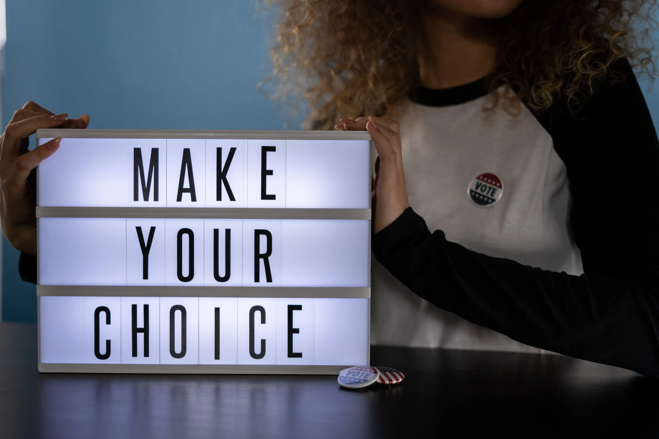 한 여성이 'make your choice'라고 적혀있는 조명을 들고 있다.