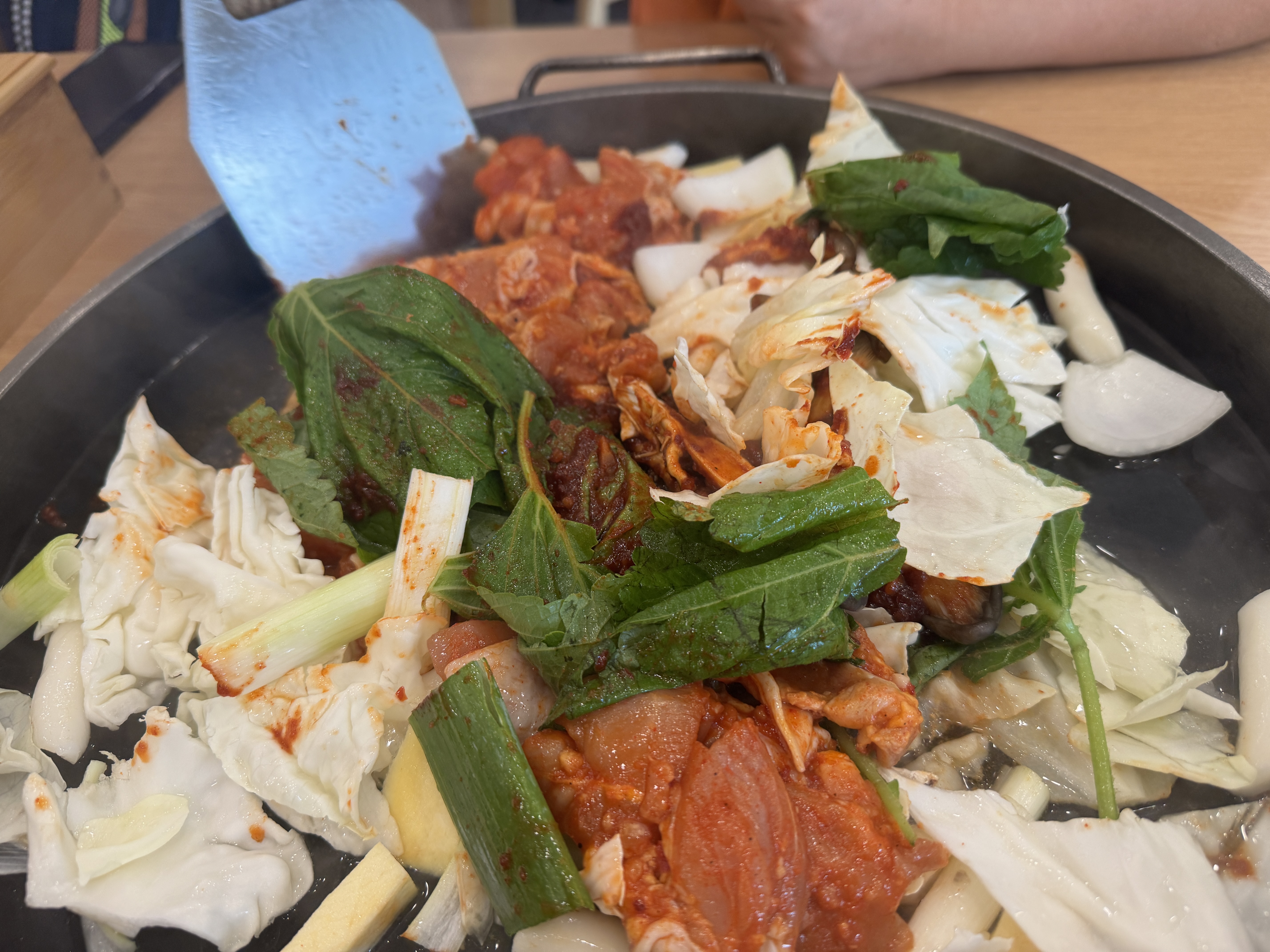 철판 위에 닭고기와 떡&amp;#44; 양배추&amp;#44; 버섯&amp;#44; 깻잎 위로 고추장 양념이 듬뿍 얹혀진 송정 닭갈비의 조리 전 모습. 