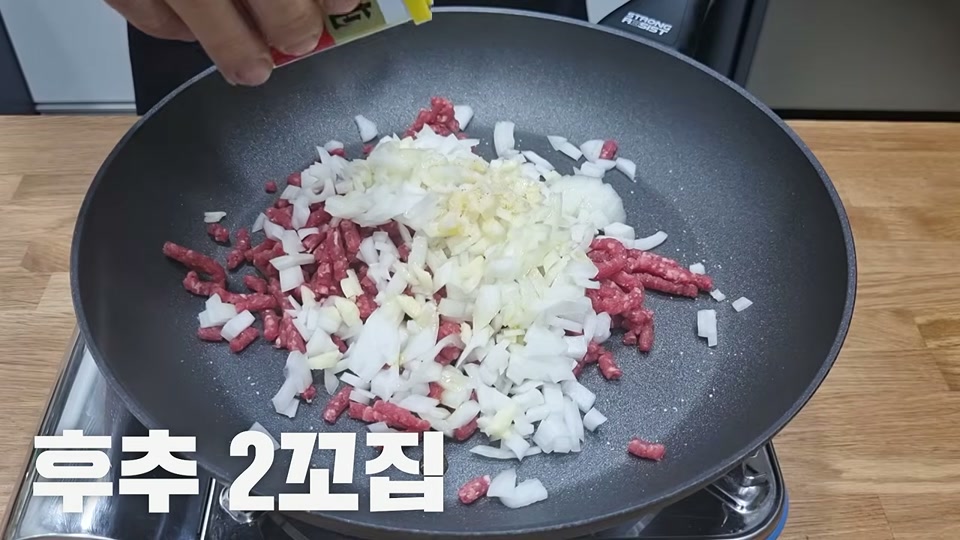 팬에서 소고기와 양파, 마늘을 볶는 장면