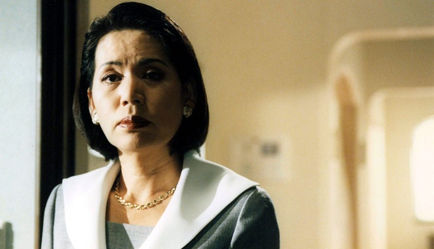 영화 올가미에서 엄마가 차분한 표정으로 문가에 서 있는 장면, 냉정한 침묵 속에 감정의 균열이 스며드는 순간