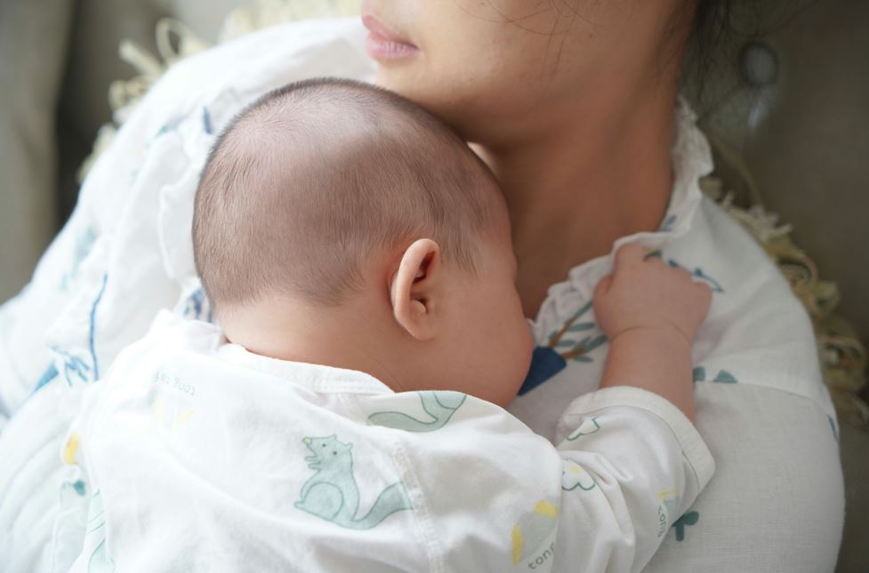 아기가 아파서 엄마 품에 기대는 사진