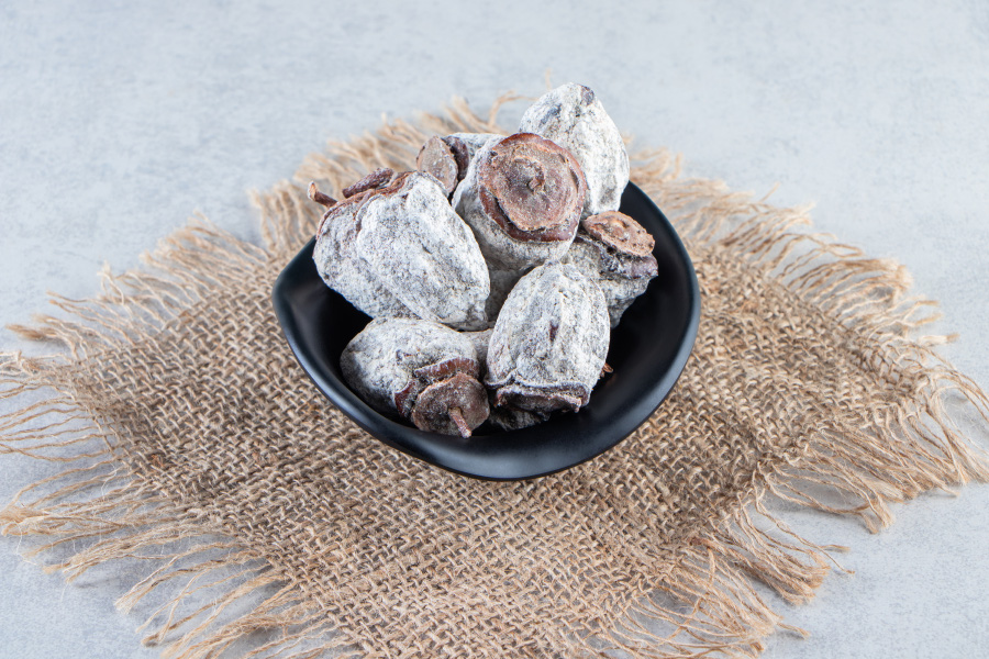 야생에서 채취를 한 감을 말려서 만든 곶감을 회색 바닥 위에 헝겊 깔판을 깔아 놓고 그 위에 검고 작은 그릇에 5~6개 정도 담아두고 찍은 사진