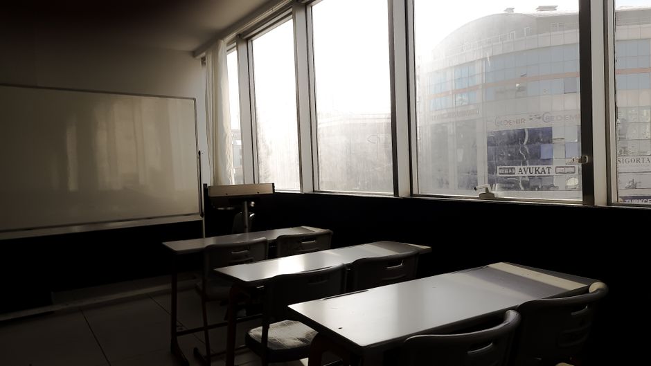 Sunlit empty classroom in Istanbul, featuring desks and a whiteboard.