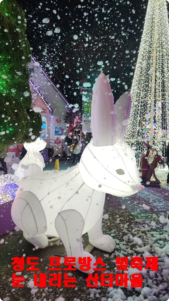 하얀 토끼모양의 등불모양 동상이 내리는 하얀눈을 맞고 있는 장면