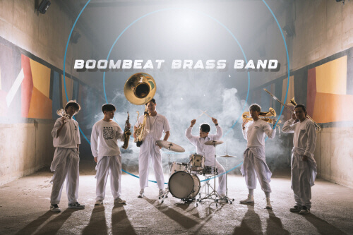 BOOMBEAT 브라스 밴드 - 금관악기 연주자들이 어두운 터널 배경 앞에서 퍼포먼스 중