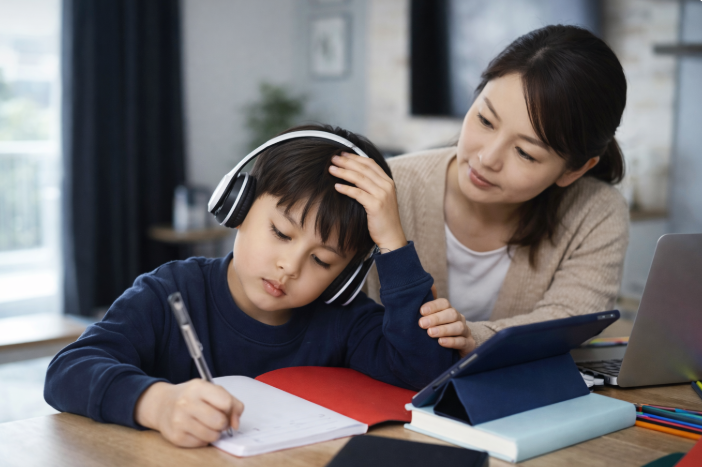 교육급여 신청을 준비하는 가정에서 어머니가 초등학생의 학습을 지켜보는 모습