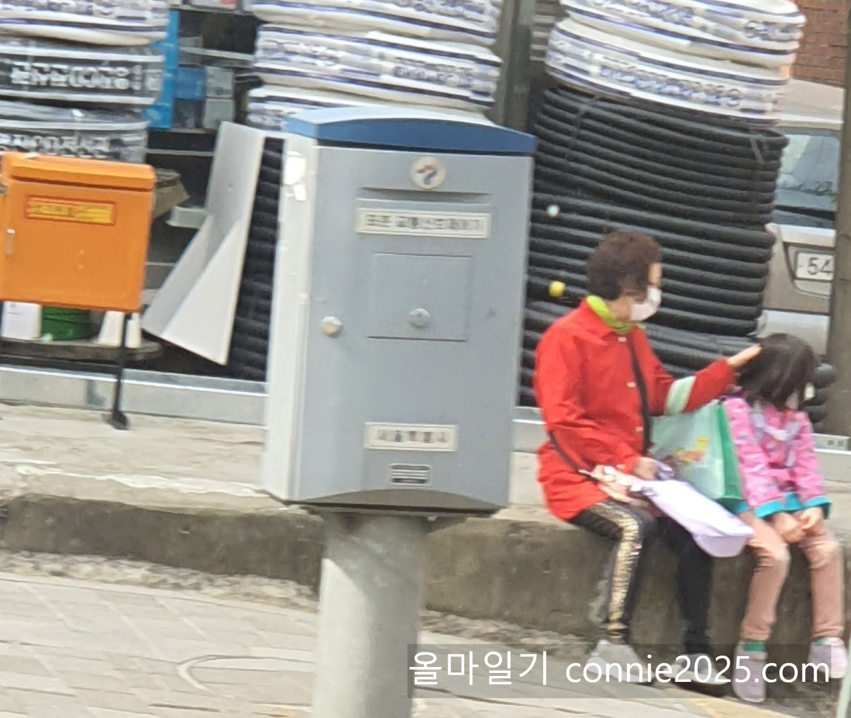 학원 차량을 기다리며 손녀 까롱이의 머리를 쓰다듬는 엄마의 모습