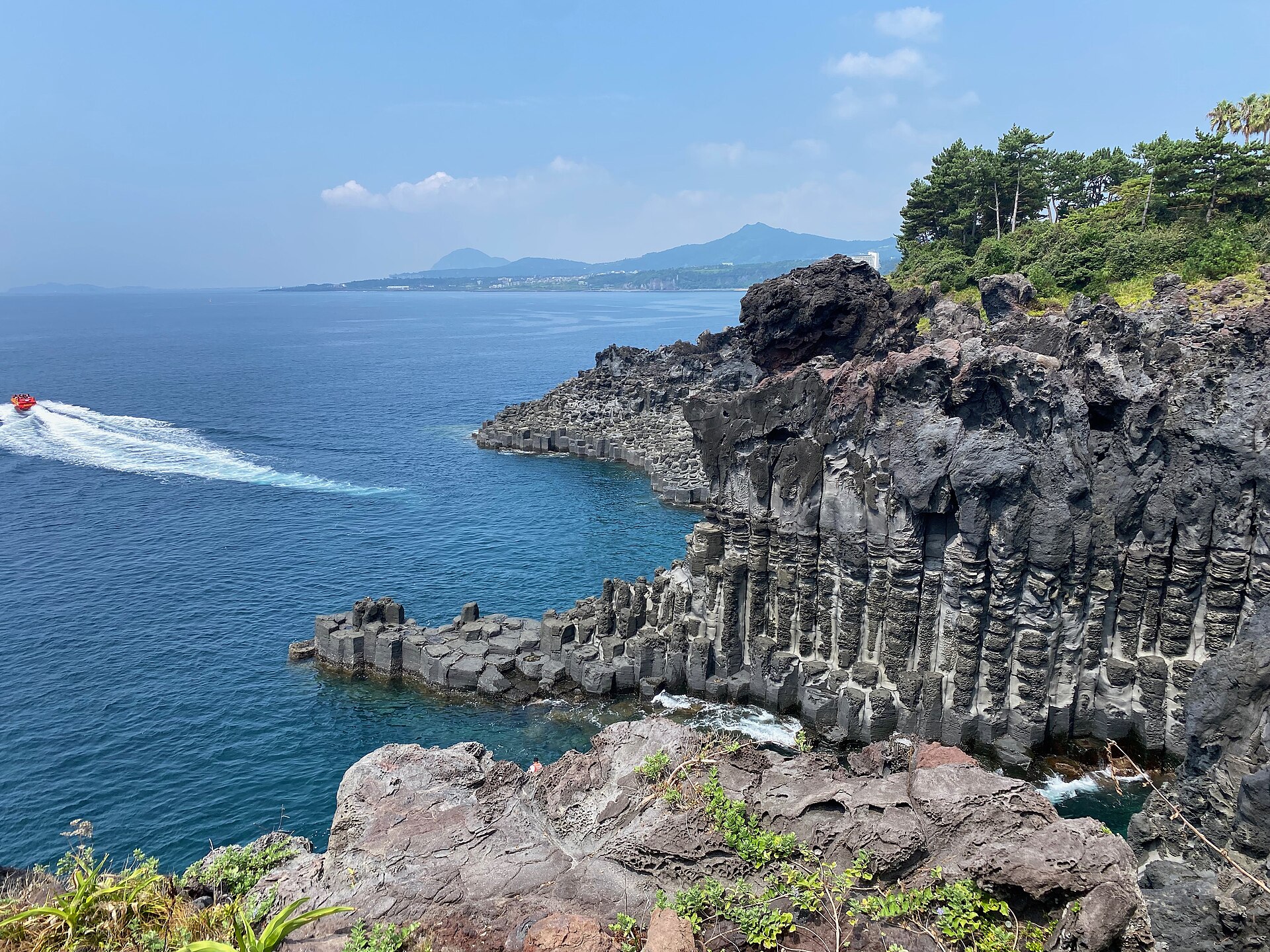 Basalt columns of Daepo Jusangjeolli Cliff above blue sea on a clear day