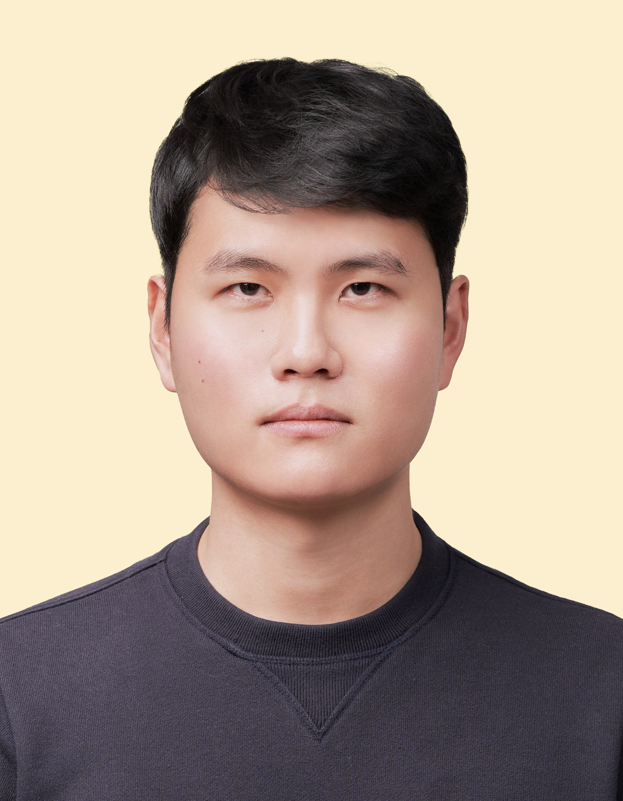 밝은 베이지색 배경 앞의 짧고 단정한 검은 머리를 한 아시아계 남성의 정면 초상화 증명사진