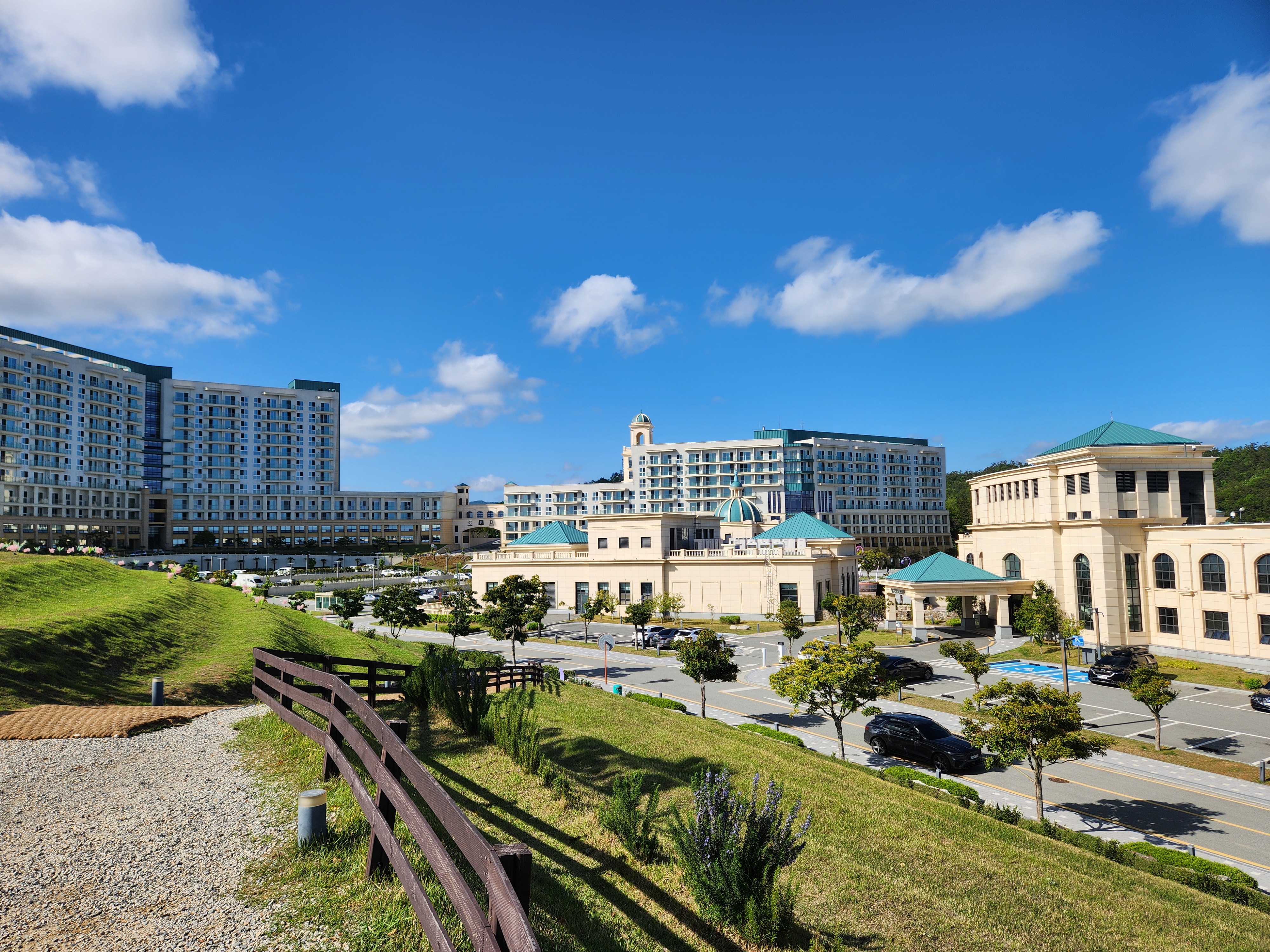 리조트 전경-푸른 잔디 산책로와-지중해풍 건물들-파란하늘과 흘러가는 구름
